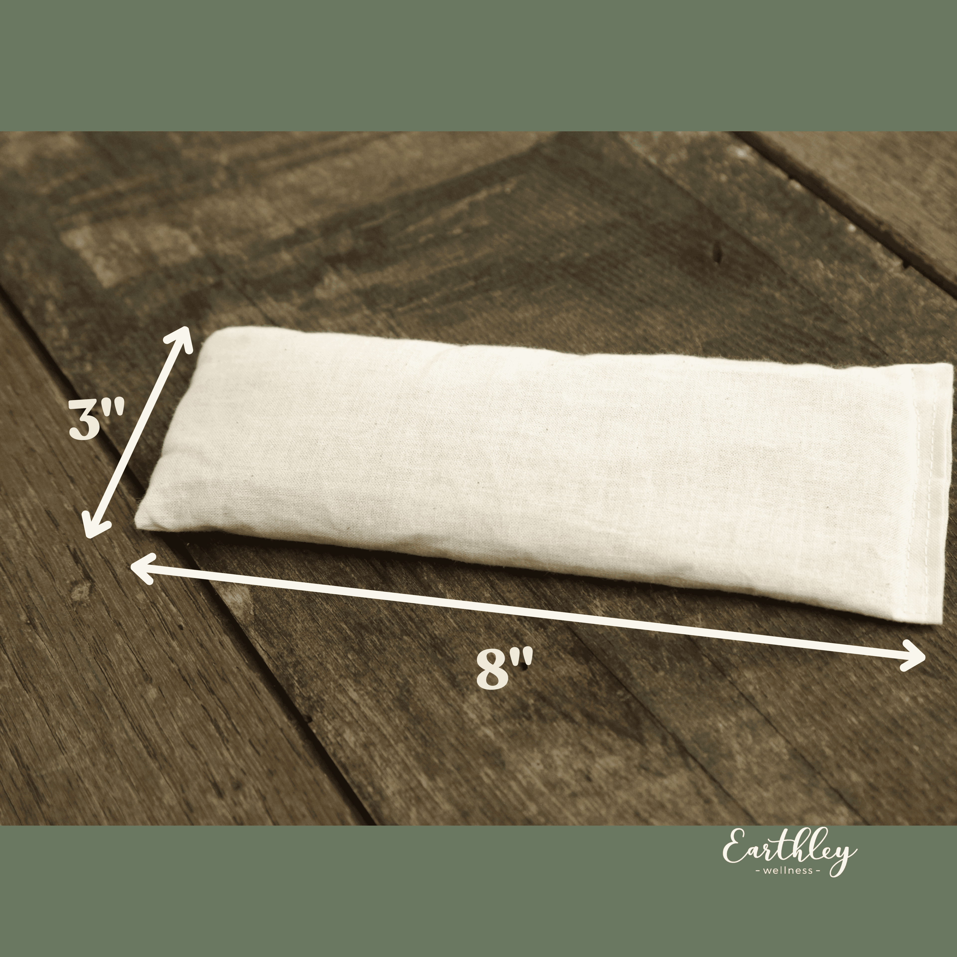 Earthley Flax Heating Pad sizing diagram showing 3 inch by 8 inch dimensions on cream cotton pad against dark gray wooden background with sage green border