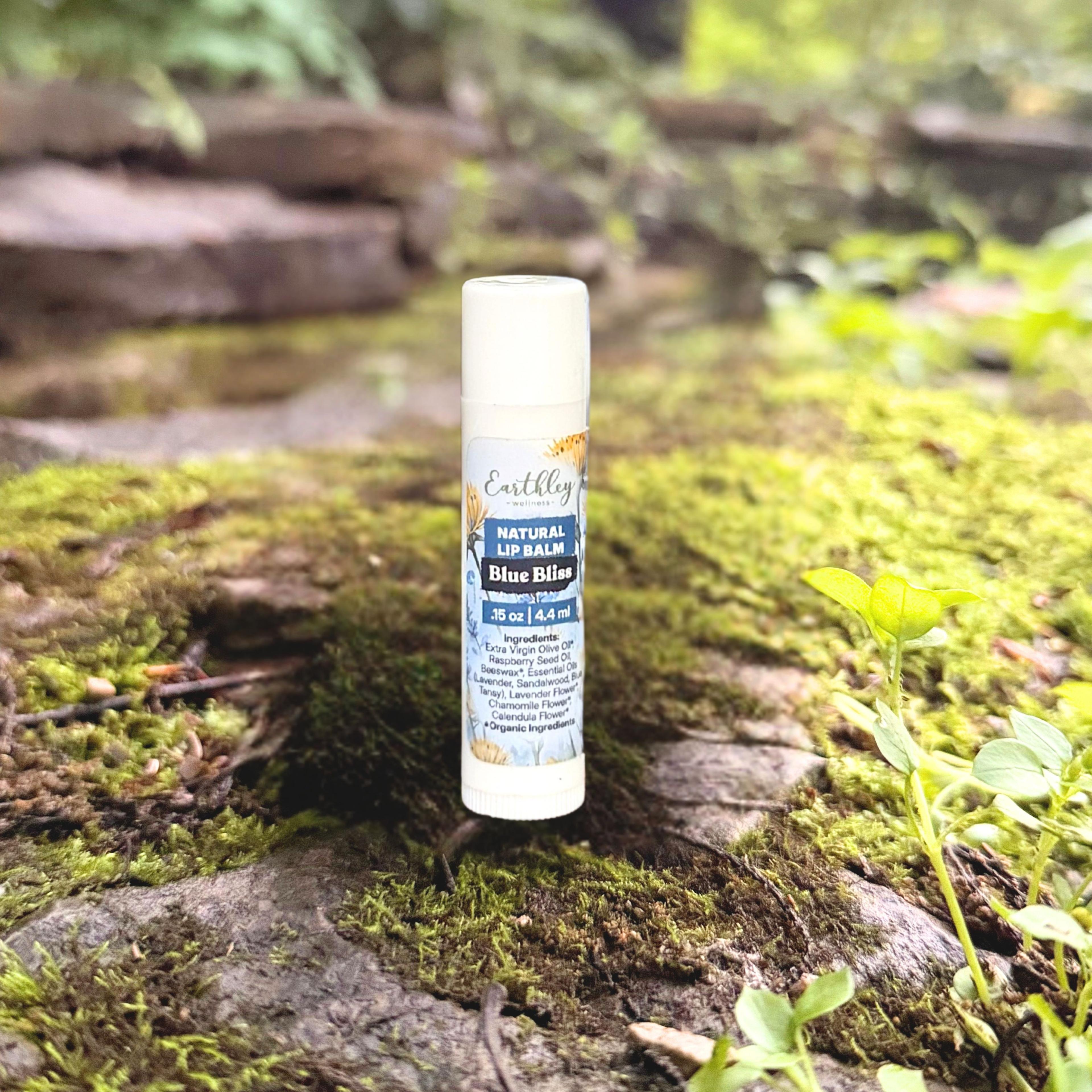 Earthley Wellness Blue Bliss Natural Lip Balm tube on moss-covered stone outdoors