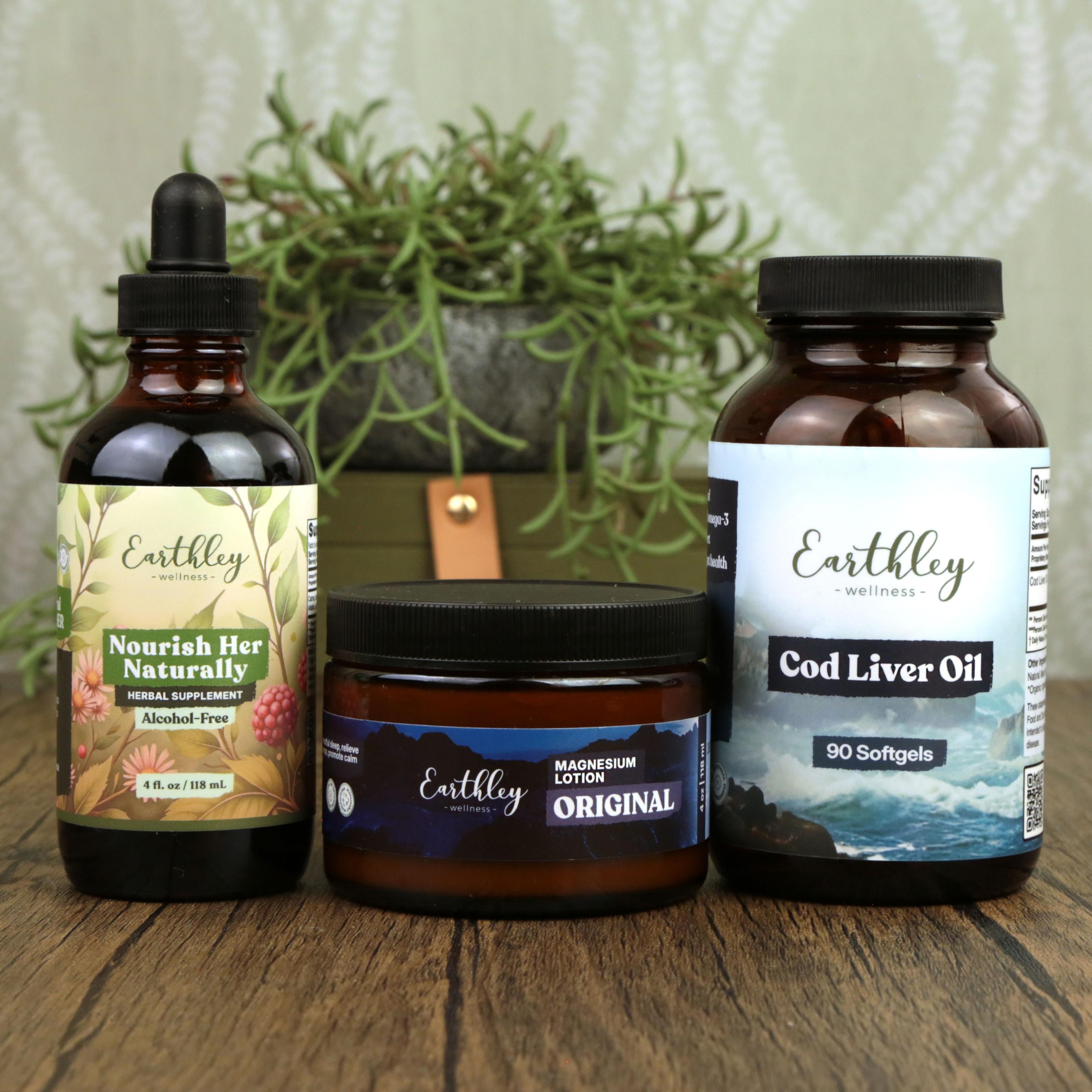 Three Earthley Wellness products on wood surface: Nourish Her Naturally tincture, Magnesium Lotion jar, and Cod Liver Oil softgels with plant backdrop