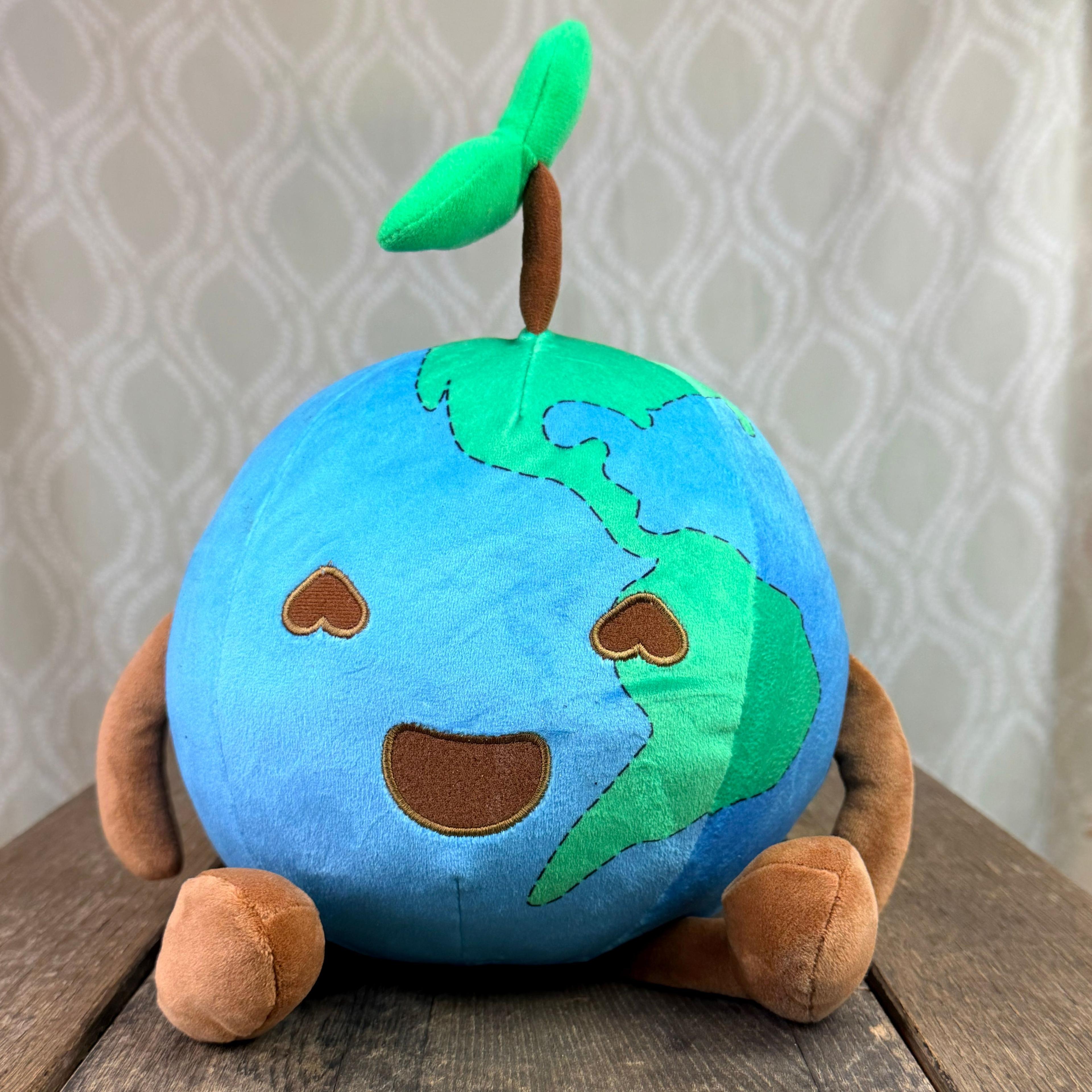 Smiling Earth plush toy with green continents, heart eyes, and a sprouting plant on top