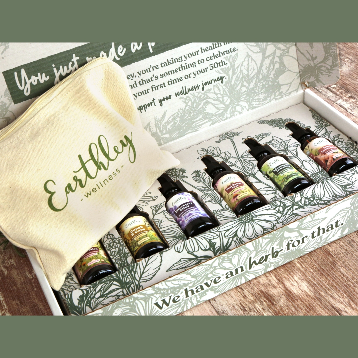 Earthley Tincture Box Set opened showing six amber tincture bottles with various colorful labels arranged in white gift box with botanical herb illustration and canvas Earthley pouch