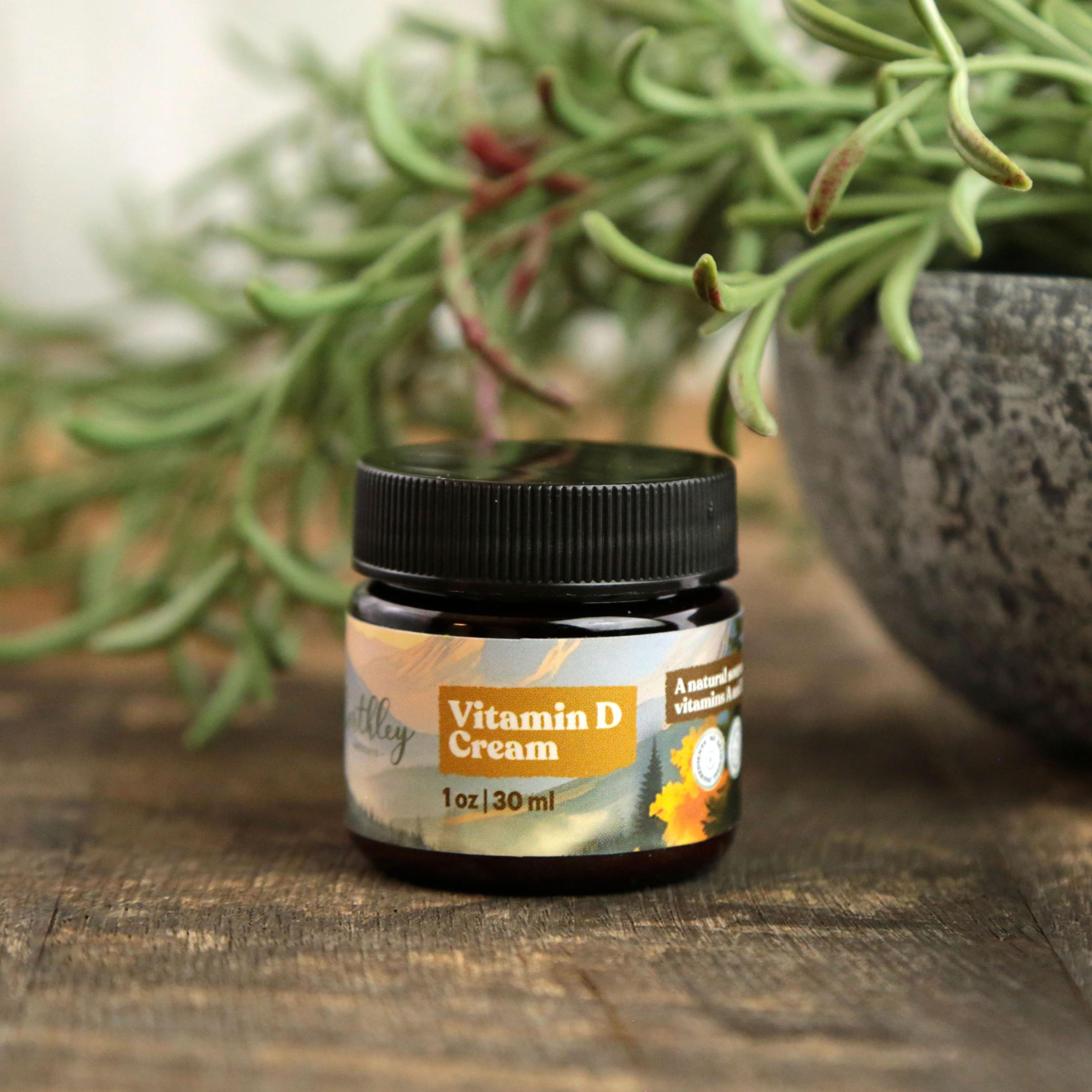 Earthley Vitamin D Cream jar (1oz/30ml) with black lid on wooden surface beside potted succulent plant