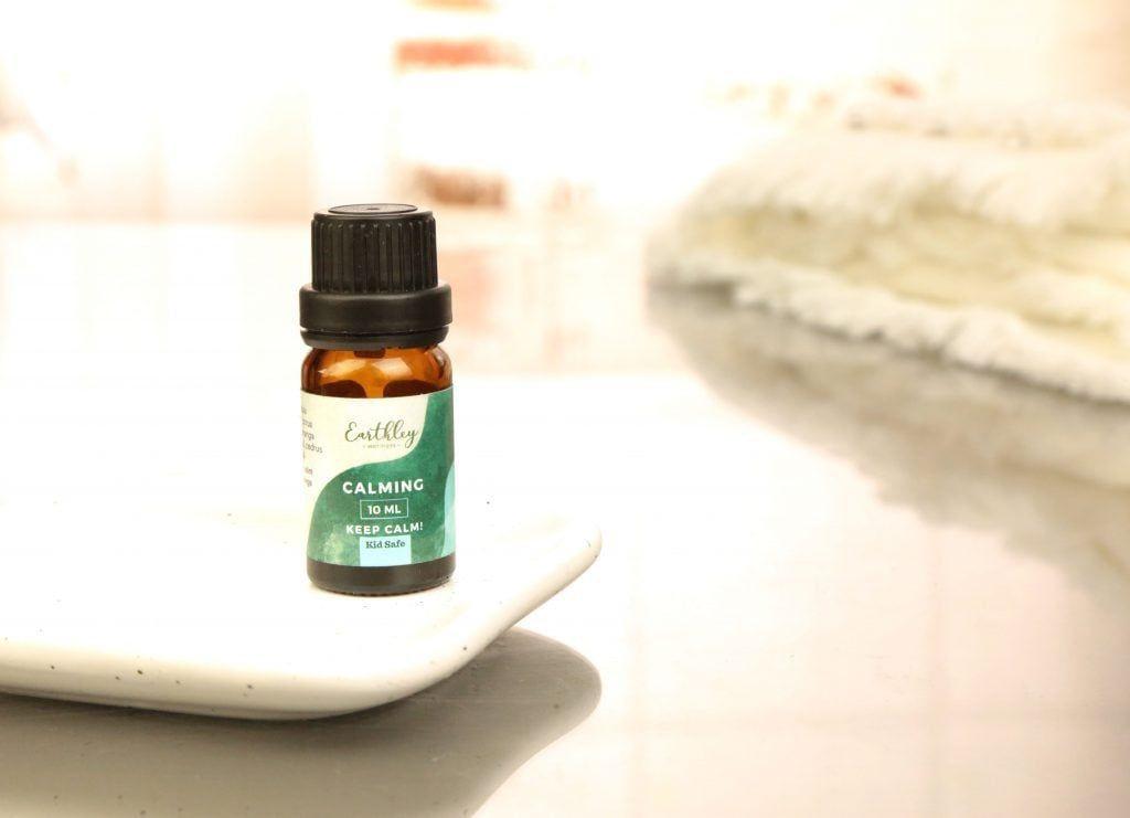 Calming essential oil blend in small amber bottle with teal label on ceramic dish
