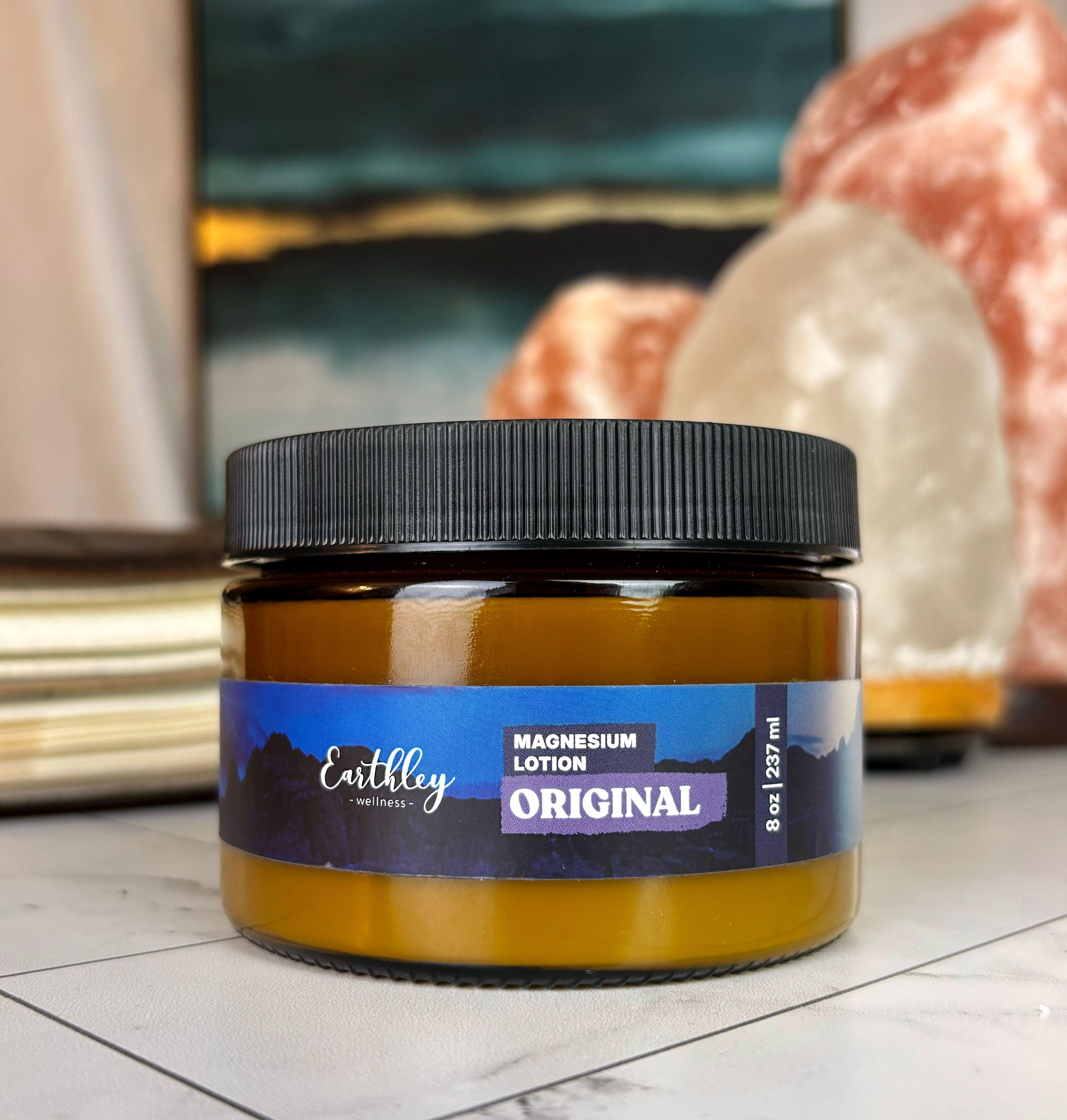 Earthley Wellness Original Magnesium Lotion jar with black lid on bathroom counter with Himalayan salt crystals
