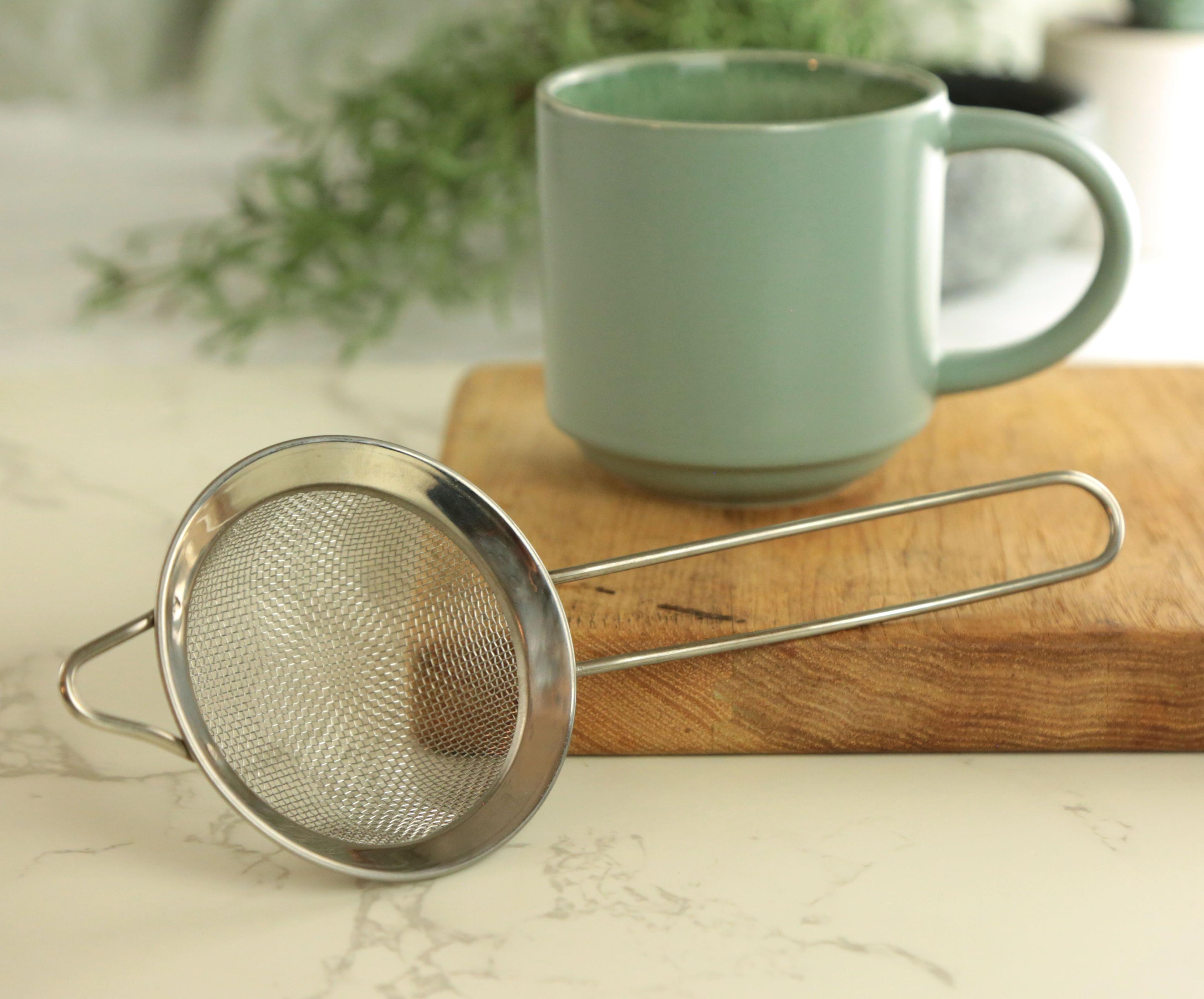 Earthley stainless steel tea infuser close-up of fine mesh ball and chain clasp for brewing loose tea on marble surface