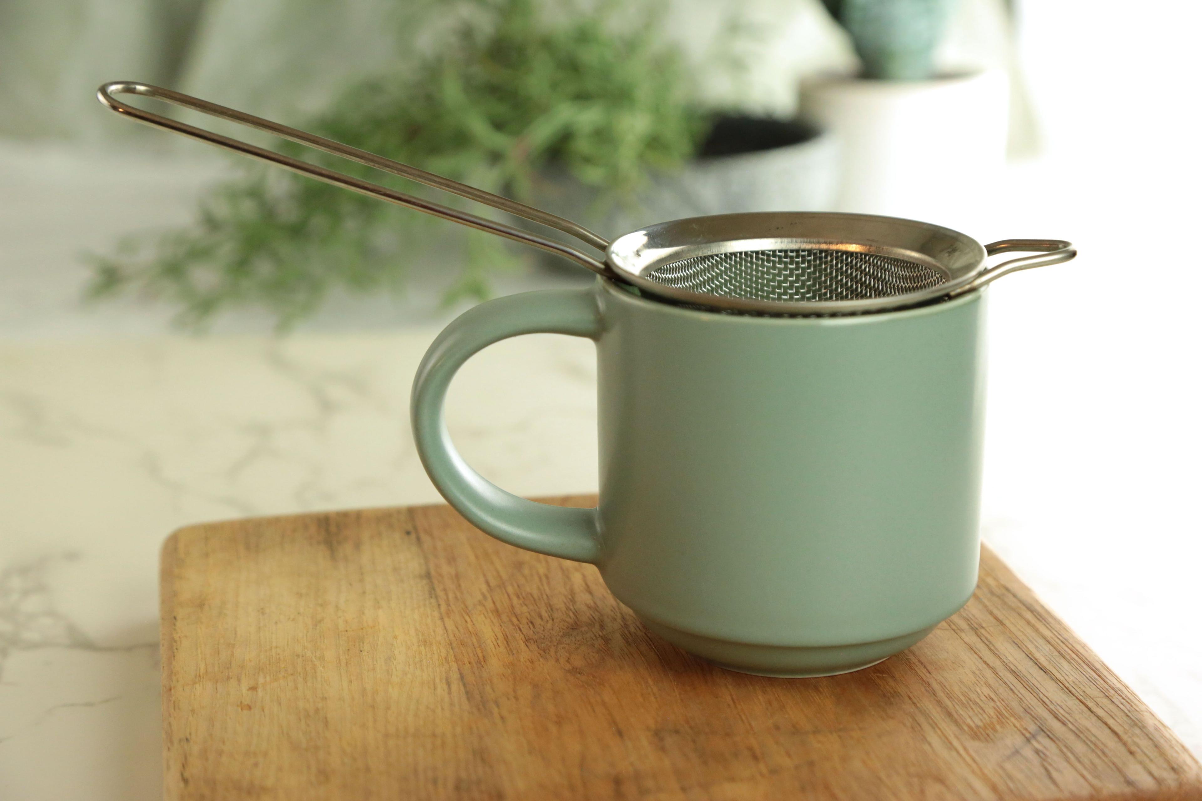 Earthley stainless steel tea infuser ball with chain showing mesh sphere design for loose leaf tea on marble surface