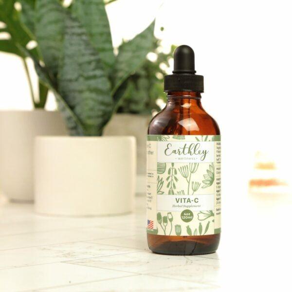 Vita-C herbal supplement in amber dropper bottle with botanical label and houseplant